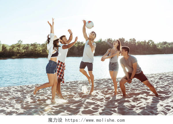 快乐的年轻朋友白天在沙滩上打排球